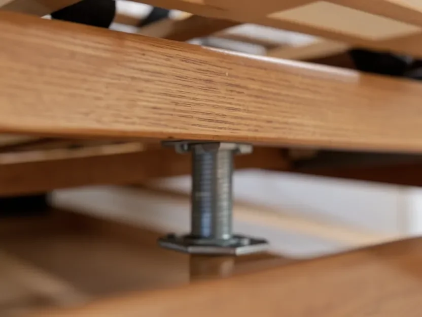 Adjustable metal center support leg installed beneath wooden bed slats