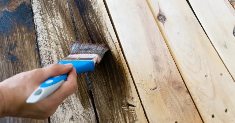 Hand brushing a clear finish onto wood planks