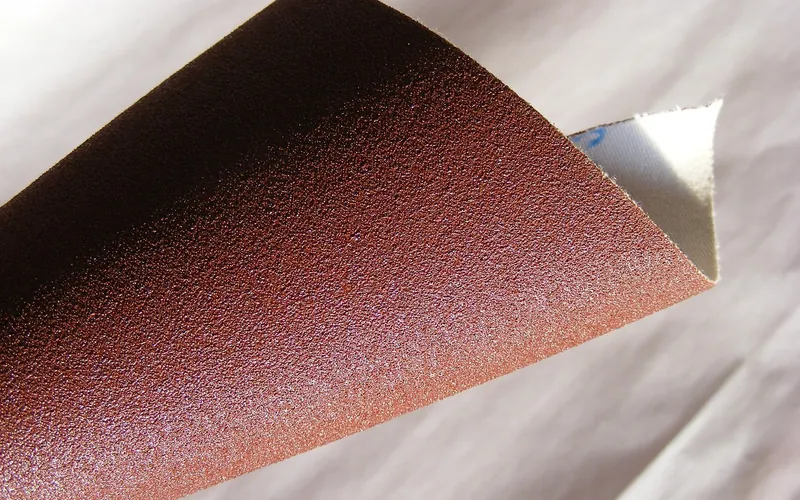 Coated abrasive sheet curled to show the grit side and the paper backing Coated abrasive sheet curled to show the grit side and the paper backing