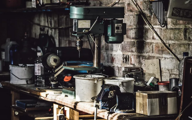 compact workbench with bench drill press and hand tools against a brick wall compact workbench with bench drill press and hand tools against a brick wall