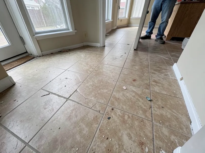 Cracked, worn resilient floor tile in an older kitchen — damaged material like this should not be swept, sanded, or lifted without testing Cracked, worn resilient floor tile in an older kitchen — damaged material like this should not be swept, sanded, or lifted without testing