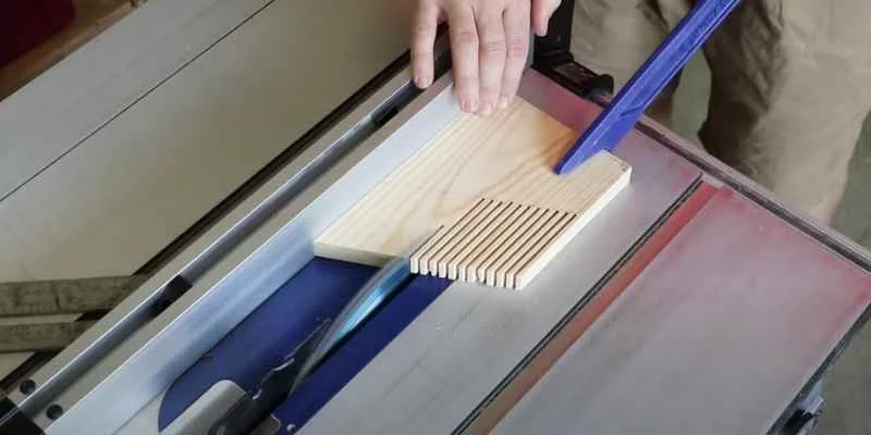Featherboard clamped to a table saw fence holding a workpiece before the blade