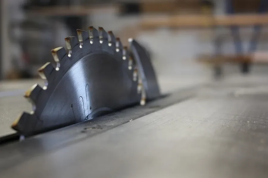 Close-up of a carbide-tipped saw blade on a saw table
