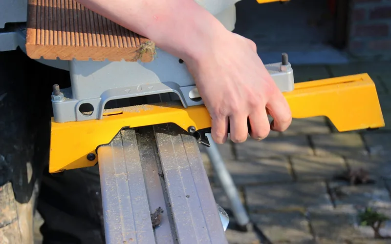 hand adjusting the miter saw's rail mechanism after loosening the fence bolts