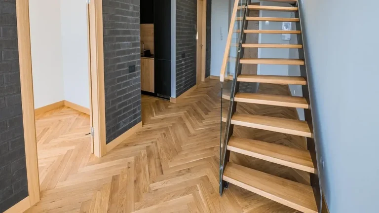 Herringbone wood plank floor in a hallway with an open staircase