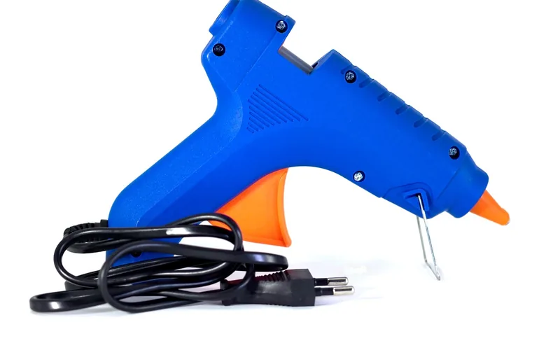 close-up of an electric hot glue gun with melted adhesive at the nozzle tip