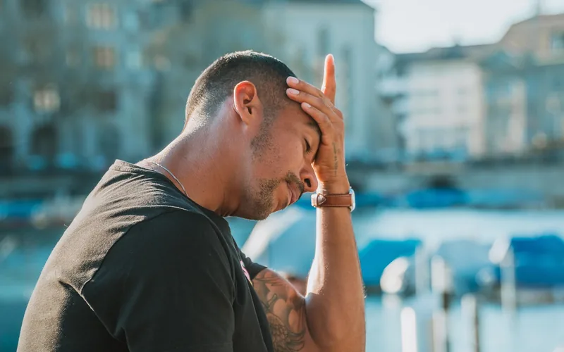 man holding his forehead with a headache, a common symptom of sinus congestion