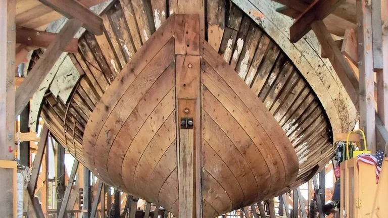 Wooden boat hull under construction in a shipyard, the kind of build where marine plywood is used