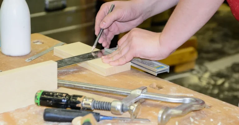 carpenter marking a wood board with a square and pencil to measure a face frame stile
