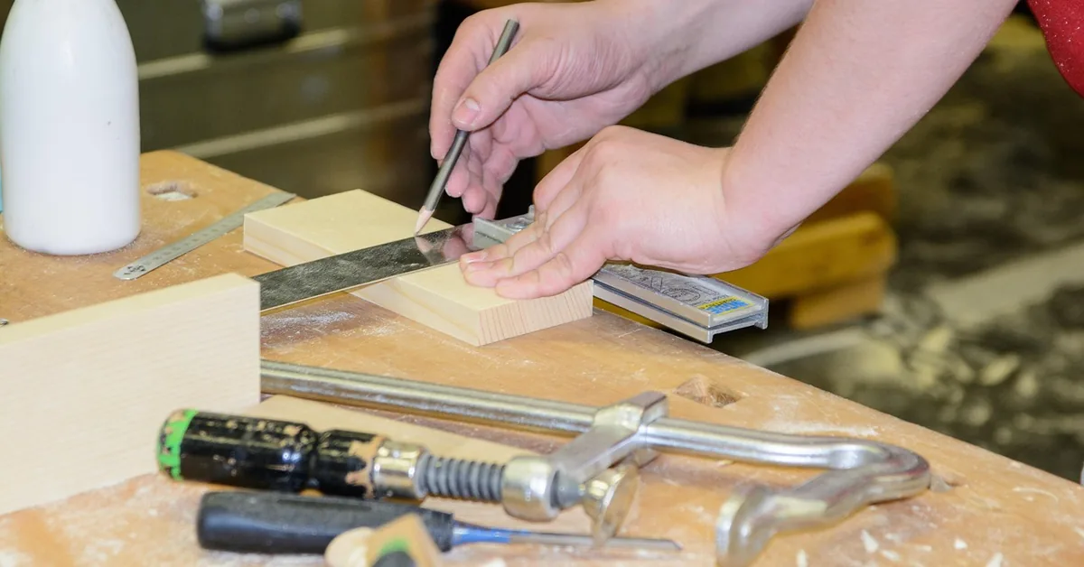 carpenter marking a wood board with a square and pencil to measure a face frame stile