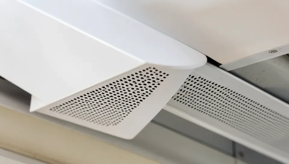 Metal soffit panels with ventilation perforations installed under an eave