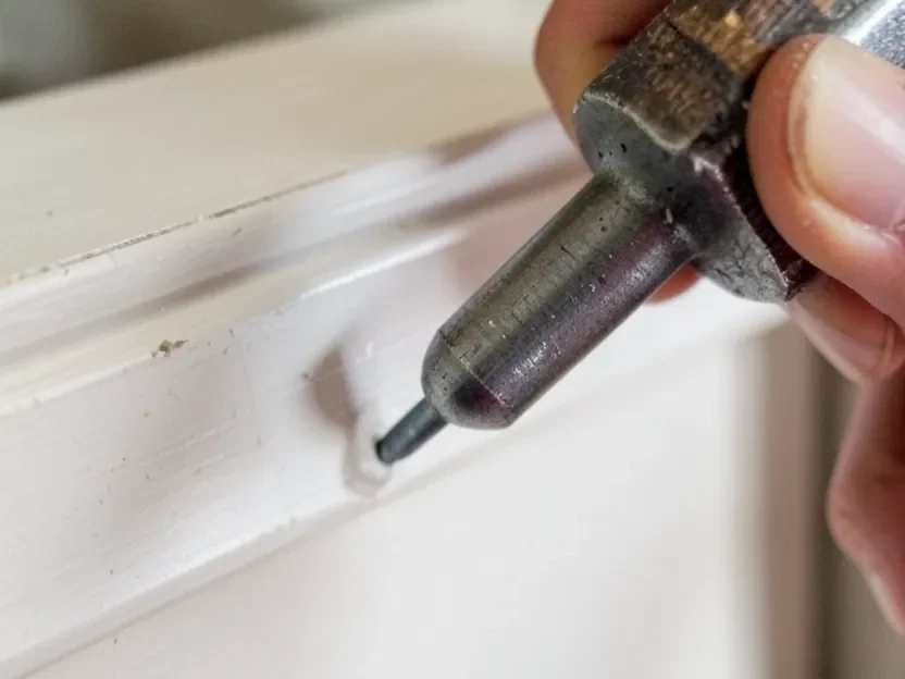 Using a nail set to countersink a hand-driven finish nail without marring the trim