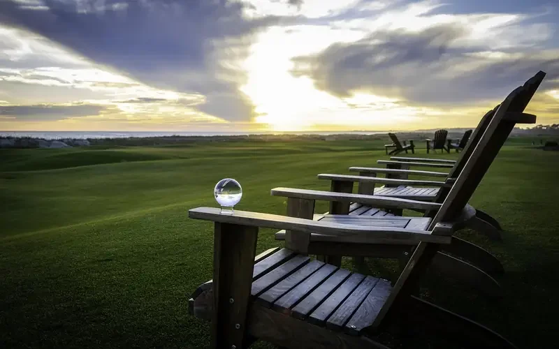 Wooden Adirondack chairs outdoors on a lawn at sunset Wooden Adirondack chairs outdoors on a lawn at sunset