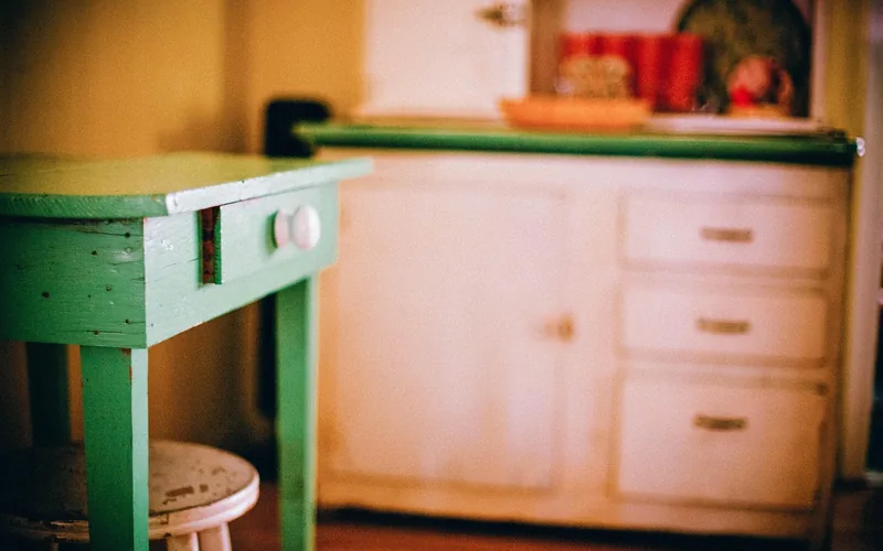 Painted wood cabinet with three stacked drawers beside a small drawer table