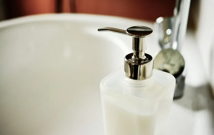 Liquid dish soap dispenser beside a sink for washing brushes