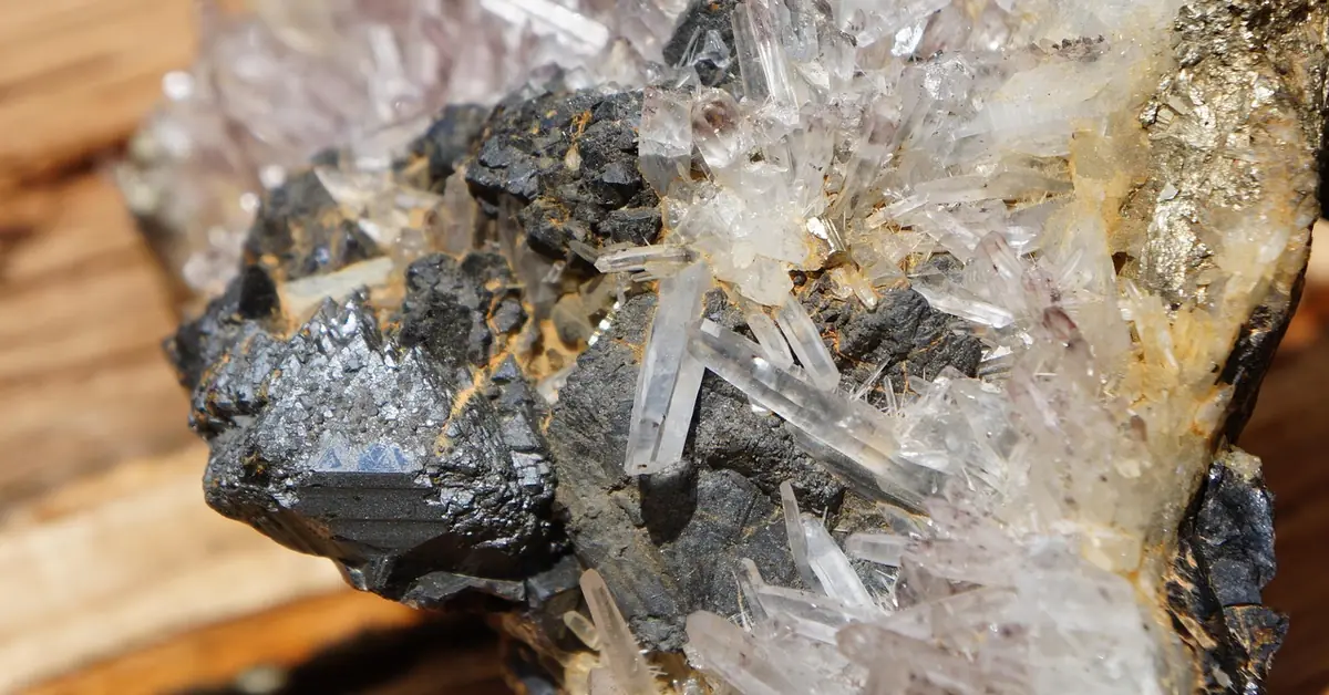 raw quartz crystal cluster resting on a cut wood surface, showing the mineral crystalline structure wood lacks