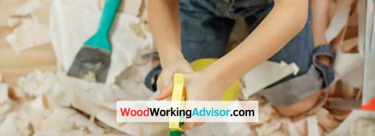 Scraping paint off a wood surface with paint chips and shavings visible