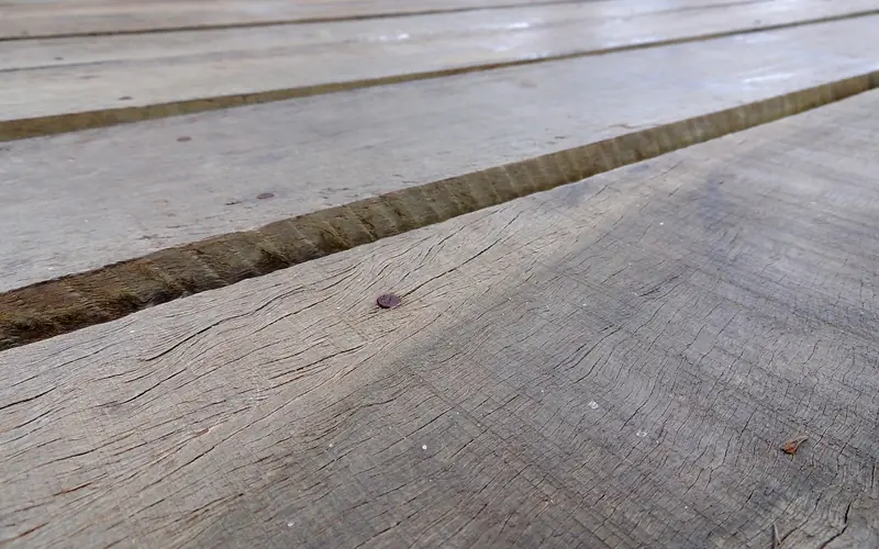 gray sun-weathered deck boards with wide gaps and a nail head gray sun-weathered deck boards with wide gaps and a nail head