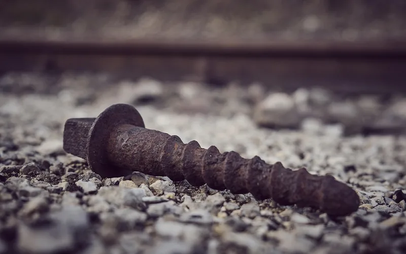 Rusted screw with corroded threads lying on gravel