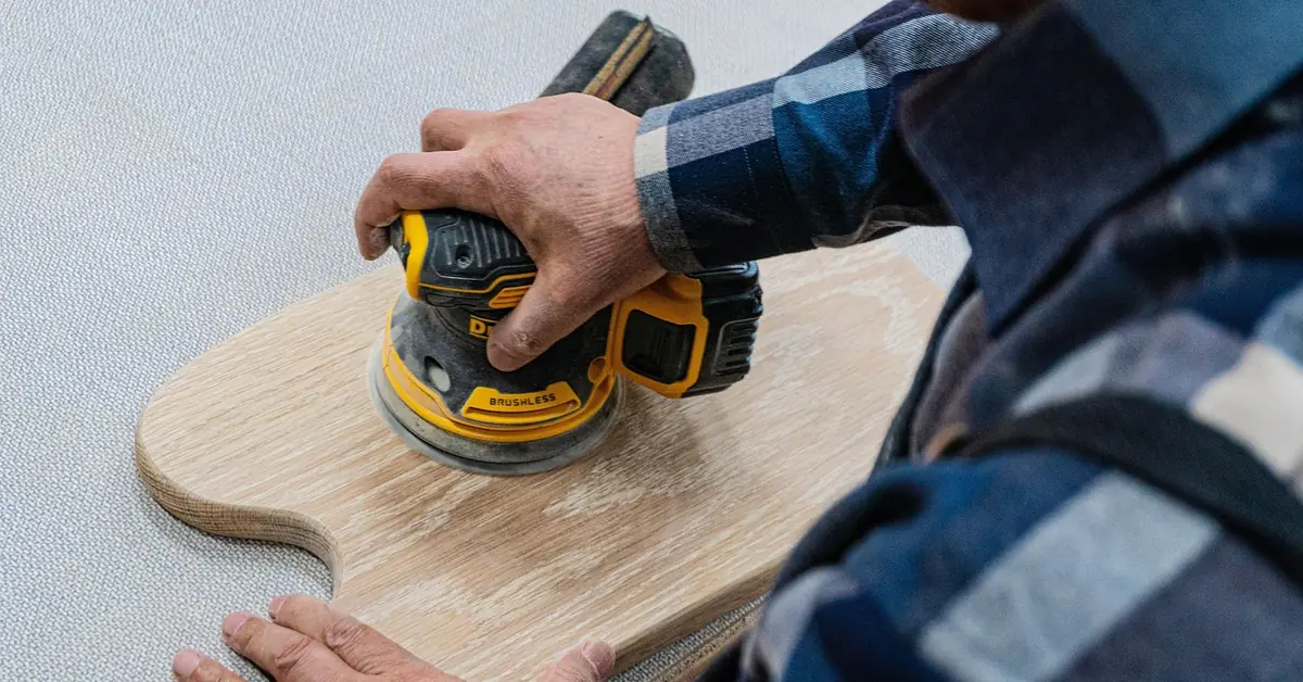sanding bare wood after removing primer with an orbital sander in a home workshop