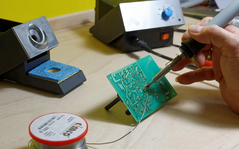 soldering iron tip positioned over a circuit board in an electronics workshop soldering iron tip positioned over a circuit board in an electronics workshop