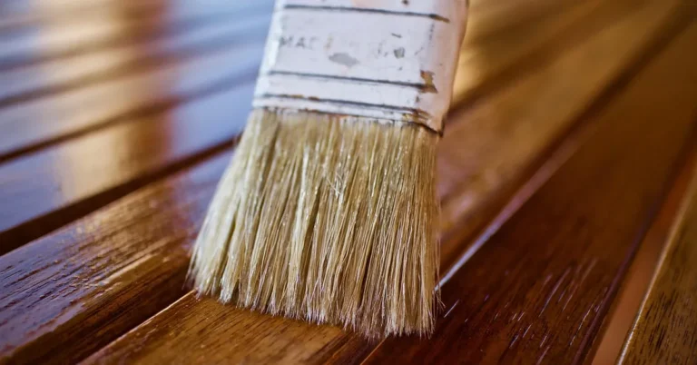 Brush applying urethane finish over wood before adding spar urethane over polyurethane