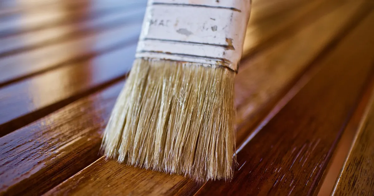 Brush applying urethane finish over wood before adding spar urethane over polyurethane