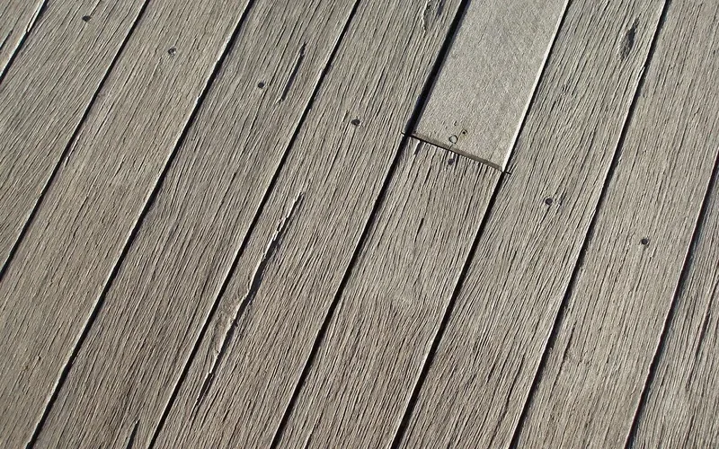 Weathered gray wood deck boards that need cleaning and drying before stain