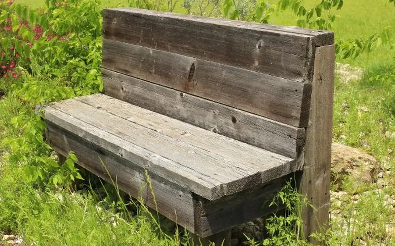 A weathered wood outdoor bench showing how unsealed wood grays over time outdoors