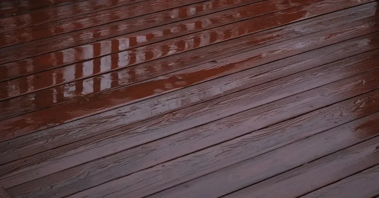 Wet stained wood deck boards after rain with standing water on the surface