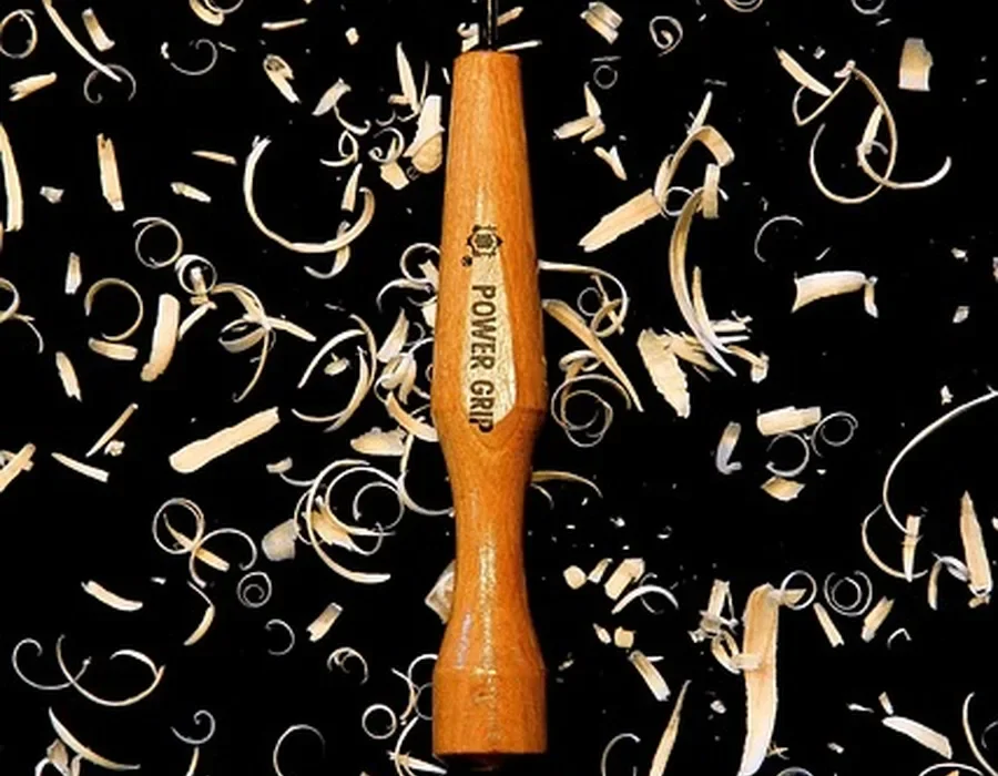 Wood carving gouge surrounded by curled shavings, the kind of carved detail that needs hand sanding