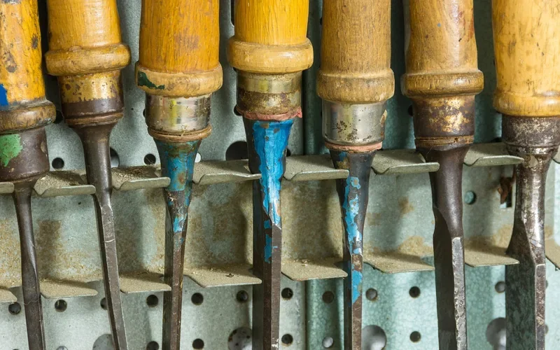 a set of chisels with wooden handles hanging on a pegboard rack in a woodworking shop a set of chisels with wooden handles hanging on a pegboard rack in a woodworking shop