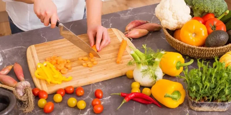 Wood cutting board being used to chop vegetables