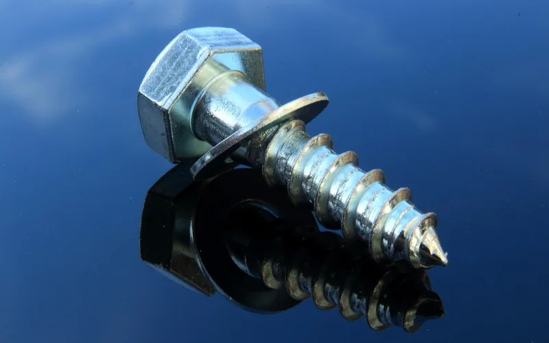 Close-up of a wood screw driven into metal, illustrating a wood-to-metal fastener connection Close-up of a wood screw driven into metal, illustrating a wood-to-metal fastener connection