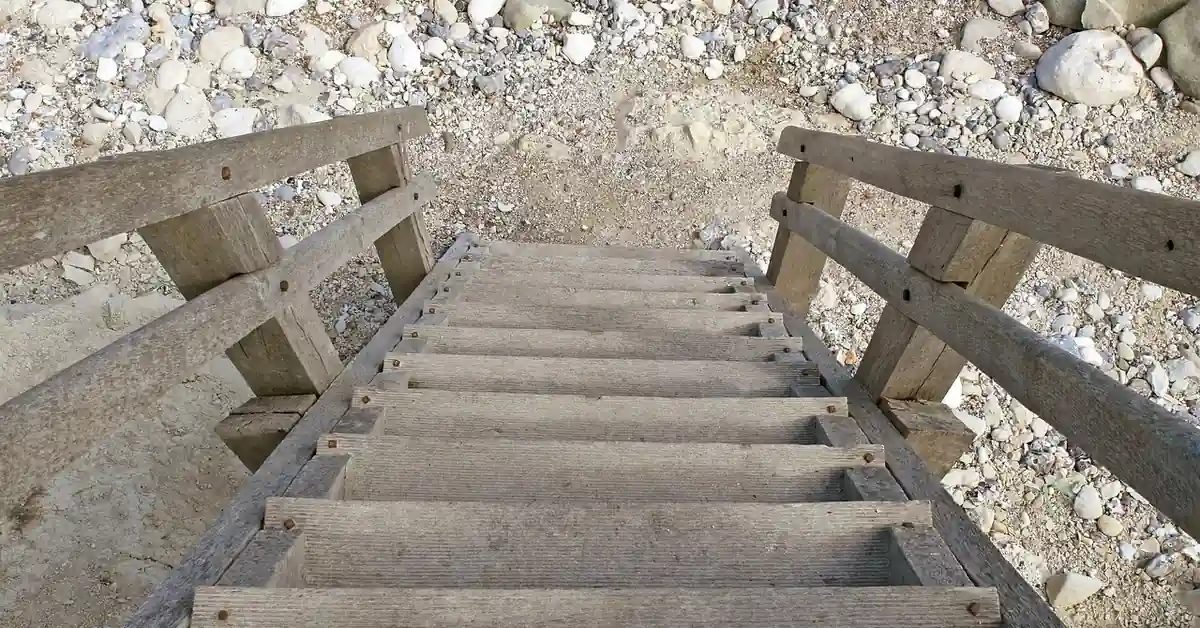 weathered wooden outdoor staircase leading down to a rocky path