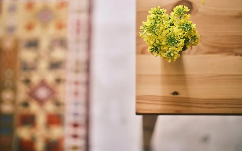 fresh yellow flowers standing in a small wooden vase on a wood table