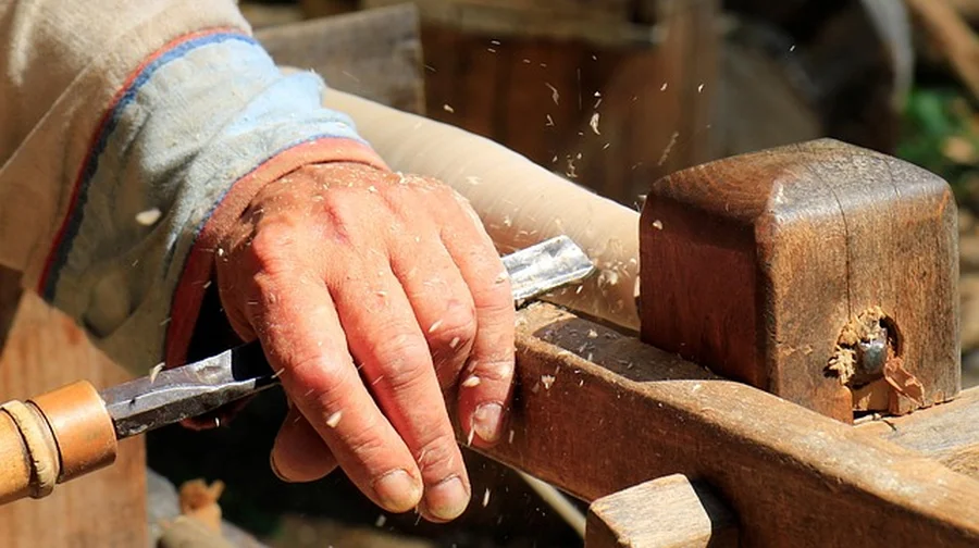 Woodturner holding a gouge against a spinning blank with shavings flying