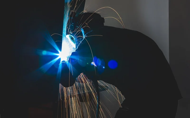 Woodworker wearing safety glasses and dust mask respirator while sanding in workshop