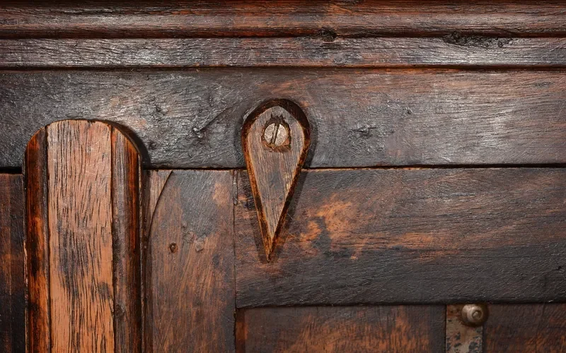 Aged finished wood cabinet surface with worn finish and grain detail