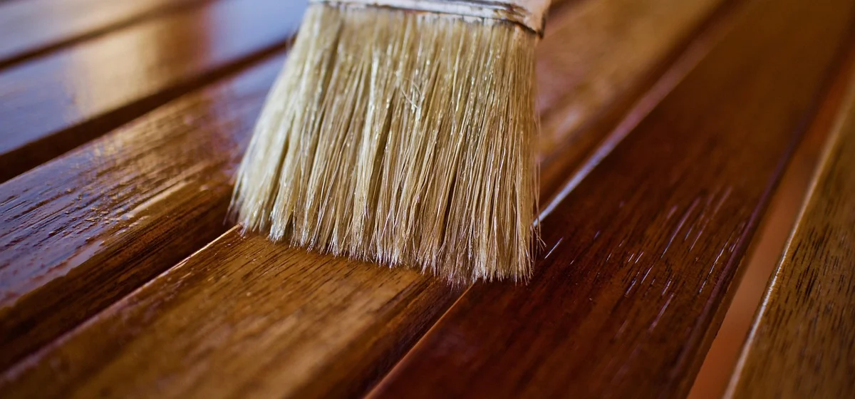 Brush applying clear protective finish to wood slats