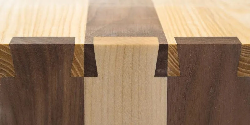 Dovetail joint showing interlocking tails and pins in contrasting light and dark wood