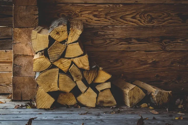 Split firewood stacked directly against a log-cabin wall Split firewood stacked directly against a log-cabin wall