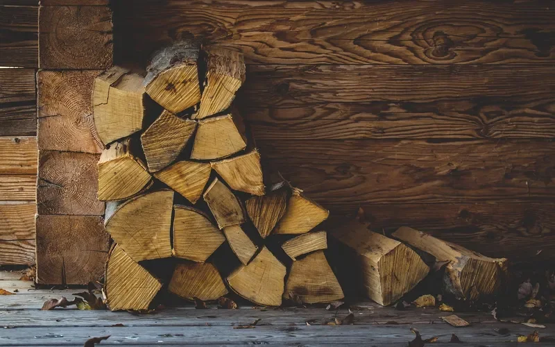 split firewood stacked directly against a wooden cabin wall