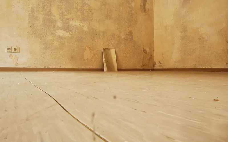 Low-angle view of a baseboard where an old wall meets the floor
