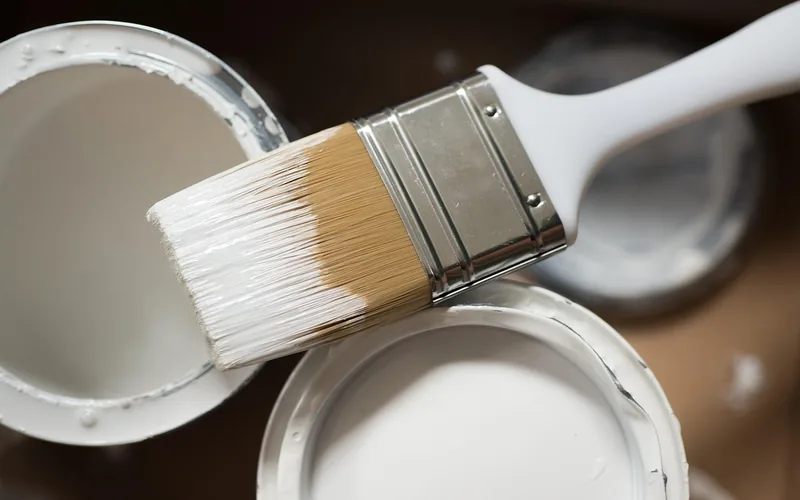 Paint brush loaded with white primer dipped from a freshly stirred can Paint brush loaded with white primer dipped from a freshly stirred can