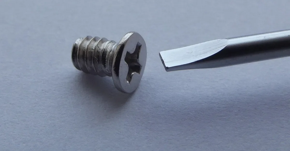 Phillips-head screw next to a flat screwdriver tip that does not fit the drive