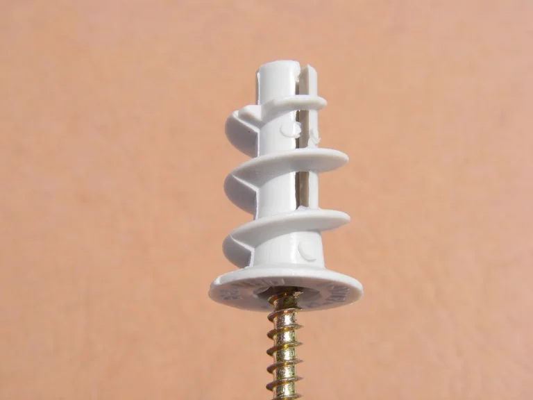 Self-drilling plastic drywall anchor with a screw on a plain wall