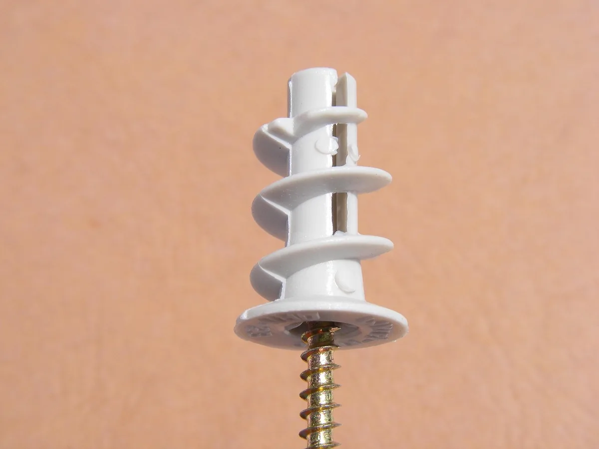Self-drilling plastic drywall anchor with a screw on a plain wall