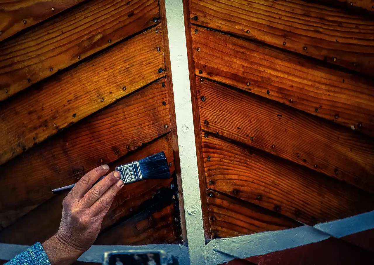 Carpenter applying finish to wood planks