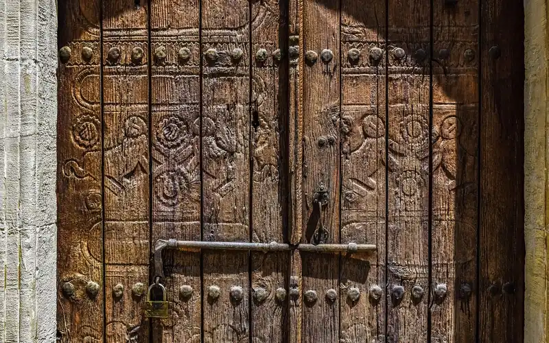 Close-up of a hand-carved solid teak wood main door panel Close-up of a hand-carved solid teak wood main door panel with a floral relief pattern